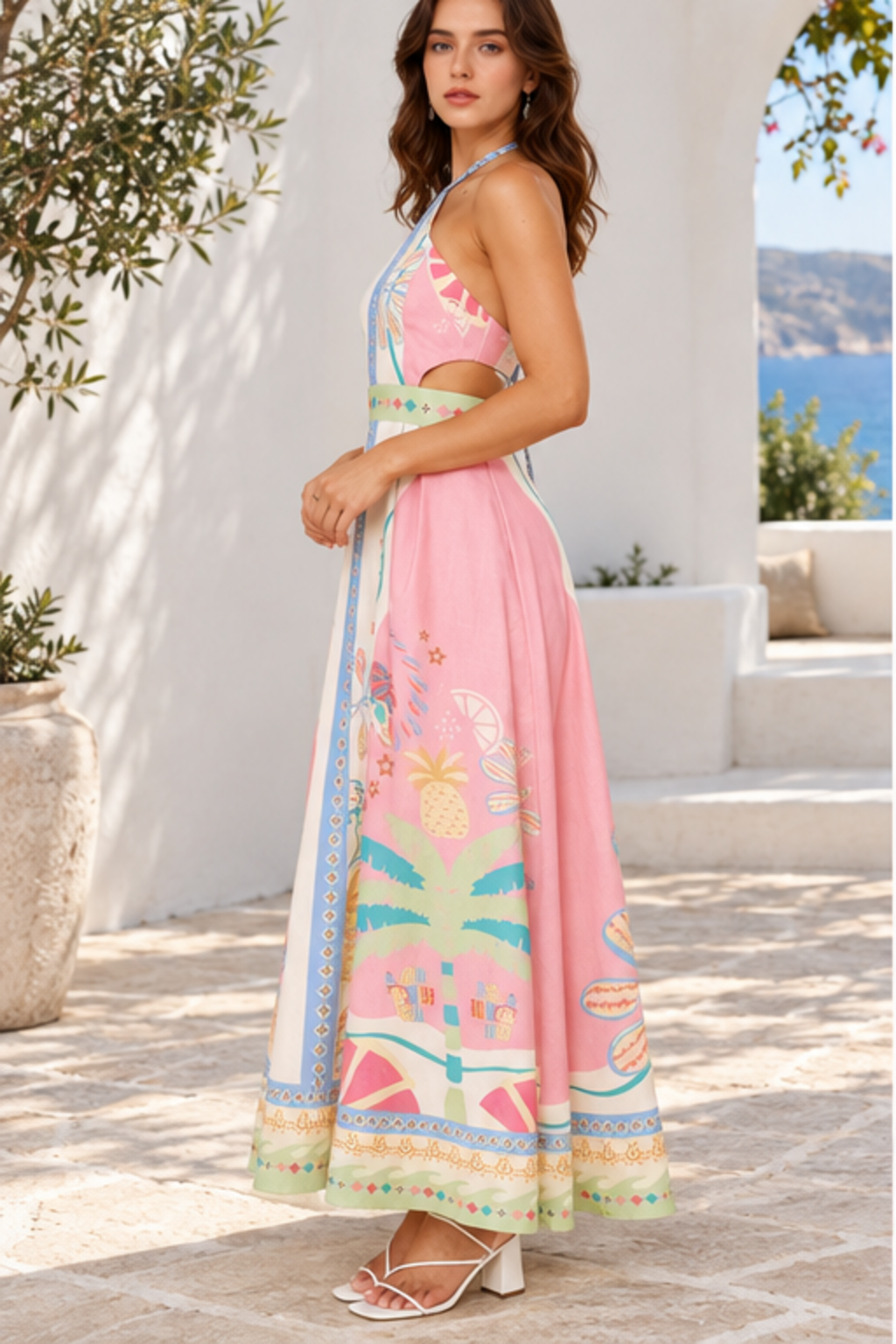 Side profile view of blush pink printed halter neck maxi dress showing waist cutout